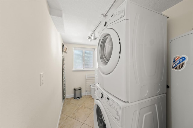 308 Canal Rd, Sarasota, FL 34242 - washroom with estacked washer and dryer, light tile patterned floors, baseboards, and a textured ceiling