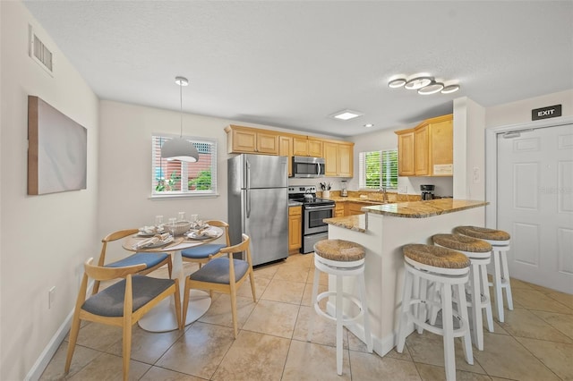 308 Canal Rd, Sarasota, FL 34242 - kitchen with stainless steel appliances, a peninsula, light brown cabinetry, a breakfast bar area, and light tile patterned flooring