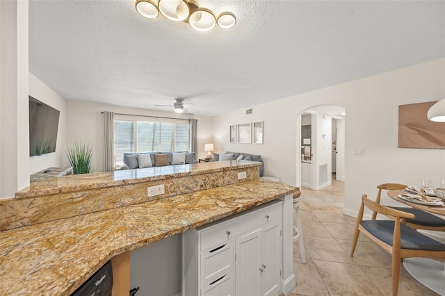 308 Canal Rd, Sarasota, FL 34242 - kitchen with white cabinetry, arched walkways, open floor plan, a textured ceiling, and light stone countertops