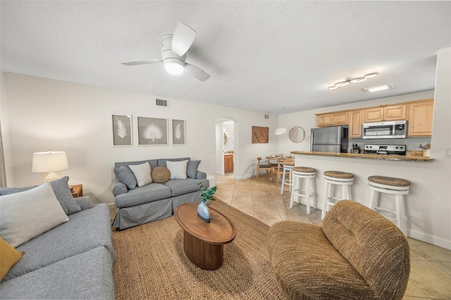 308 Canal Rd, Sarasota, FL 34242 - living area with arched walkways, light tile patterned floors, baseboards, a ceiling fan, and a textured ceiling