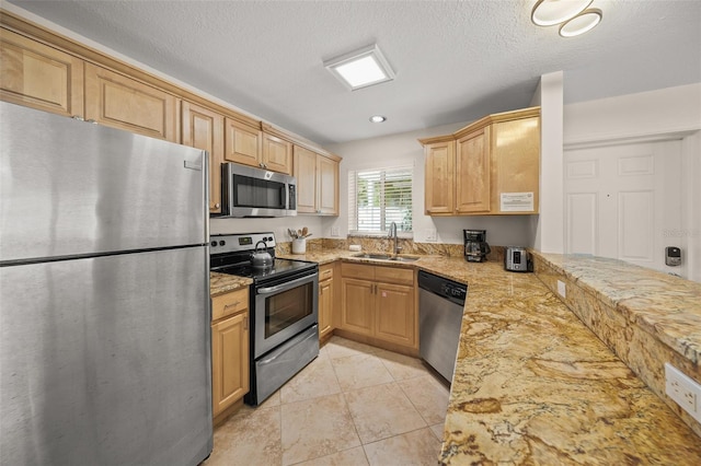 308 Canal Rd, Sarasota, FL 34242 - kitchen featuring appliances with stainless steel finishes, a sink, light stone countertops, light tile patterned floors, and light brown cabinetry