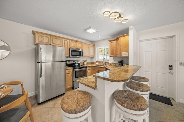 308 Canal Rd, Sarasota, FL 34242 - kitchen with appliances with stainless steel finishes, a peninsula, a breakfast bar, light tile patterned flooring, and a sink
