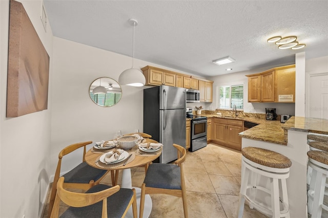 308 Canal Rd, Sarasota, FL 34242 - kitchen with stainless steel appliances, a peninsula, light stone counters, a breakfast bar, and light tile patterned floors
