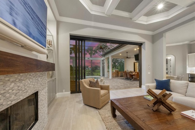 8312 Catamaran Cir, Lakewood Ranch, FL 34202 - living room with a tile fireplace, light wood-style floors, beamed ceiling, ornamental molding, and arched walkways