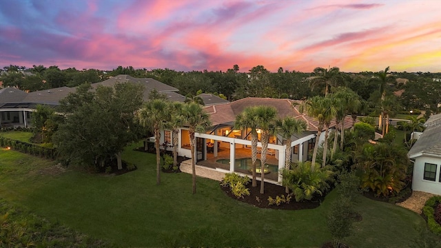 8312 Catamaran Cir, Lakewood Ranch, FL 34202 - back of property at dusk featuring a yard, stucco siding, and a tile roof