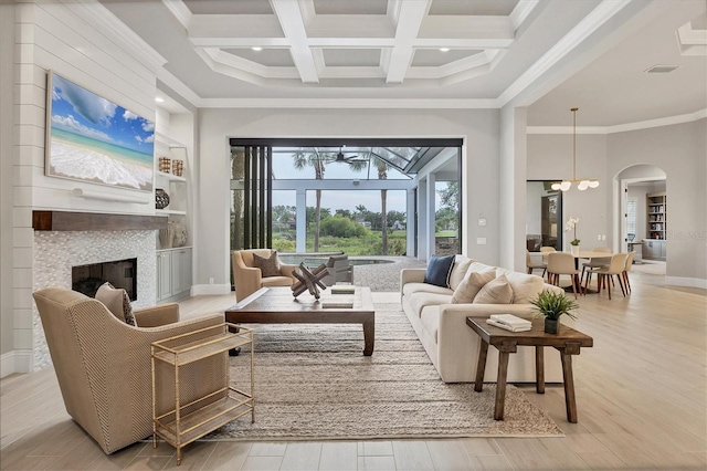 8312 Catamaran Cir, Lakewood Ranch, FL 34202 - living area featuring light wood-type flooring, a tile fireplace, beamed ceiling, a towering ceiling, and arched walkways