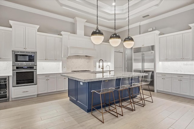8312 Catamaran Cir, Lakewood Ranch, FL 34202 - kitchen featuring built in appliances, a tray ceiling, ornamental molding, white cabinets, and backsplash