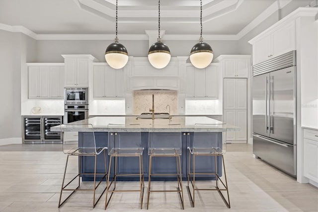 8312 Catamaran Cir, Lakewood Ranch, FL 34202 - kitchen with built in appliances, beverage cooler, a raised ceiling, white cabinetry, and tasteful backsplash