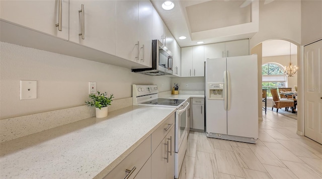5698 Country Walk Ln, Sarasota, FL 34233 - kitchen with white appliances, arched walkways, white cabinets, a chandelier, and recessed lighting