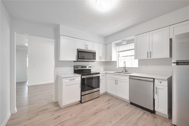 478 Orange Dr NW, Port Charlotte, FL 33952 - kitchen featuring stainless steel appliances, a sink, light countertops, white cabinets, and a textured ceiling