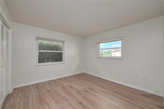 478 Orange Dr NW, Port Charlotte, FL 33952 - unfurnished bedroom featuring light wood-style flooring, a closet, baseboards, and a textured ceiling