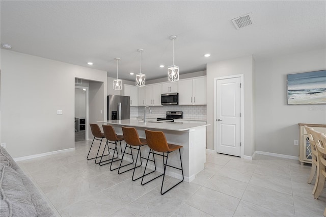 9148 Royal River Cir, Parrish, FL 34219 - kitchen featuring stainless steel appliances, light countertops, decorative backsplash, white cabinets, and a breakfast bar