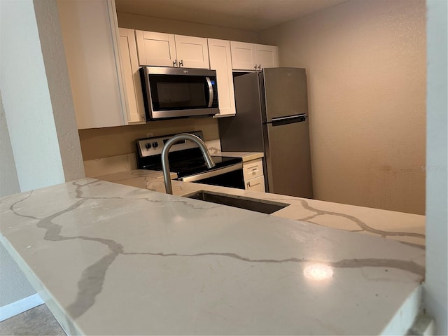 2650 Coconut Bay Ln Unit 521, Sarasota, FL 34237 - kitchen featuring stainless steel appliances, light stone countertops, white cabinets, and a peninsula