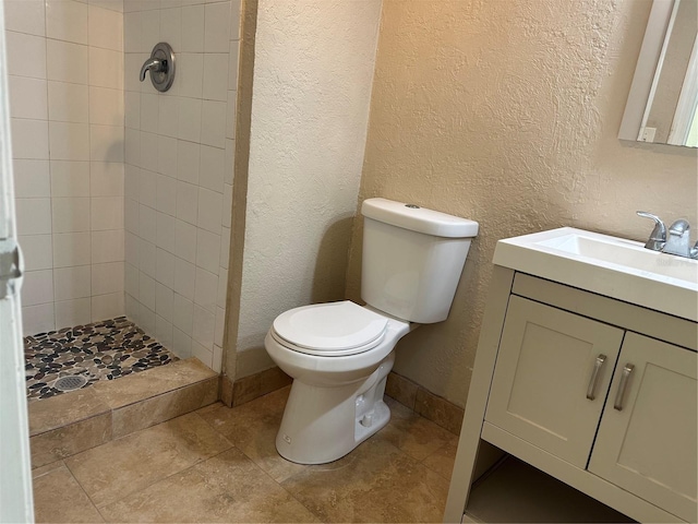 2650 Coconut Bay Ln Unit 521, Sarasota, FL 34237 - bathroom featuring a textured wall, toilet, tiled shower, vanity, and baseboards