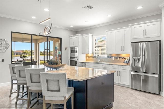 5011 Tivoli Run, Bradenton, FL 34211 - kitchen featuring appliances with stainless steel finishes, a sink, a center island, white cabinets, and decorative backsplash