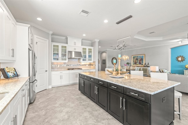 5011 Tivoli Run, Bradenton, FL 34211 - kitchen featuring under cabinet range hood, dark cabinets, appliances with stainless steel finishes, ornamental molding, and white cabinets