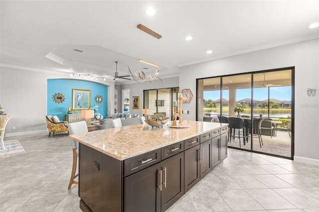 5011 Tivoli Run, Bradenton, FL 34211 - kitchen featuring ornamental molding, a kitchen breakfast bar, a kitchen island, a ceiling fan, and light stone countertops