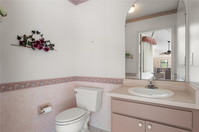 4622 34th Ct E, Bradenton, FL 34203 - bathroom with toilet, vanity, ceiling fan, and a wainscoted wall