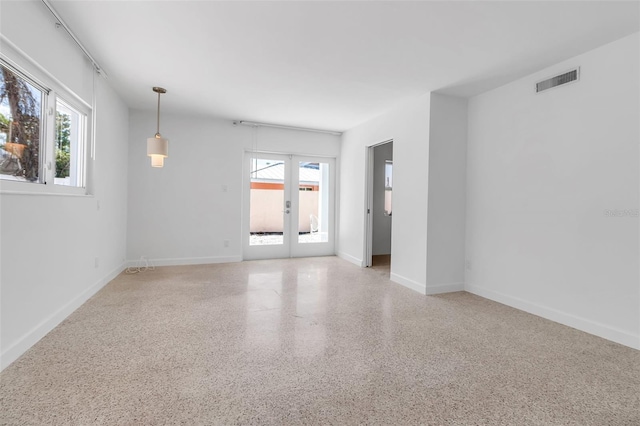 130 N Adams Dr, Sarasota, FL 34236 - empty room featuring french doors, plenty of natural light, dark speckled floor, and baseboards