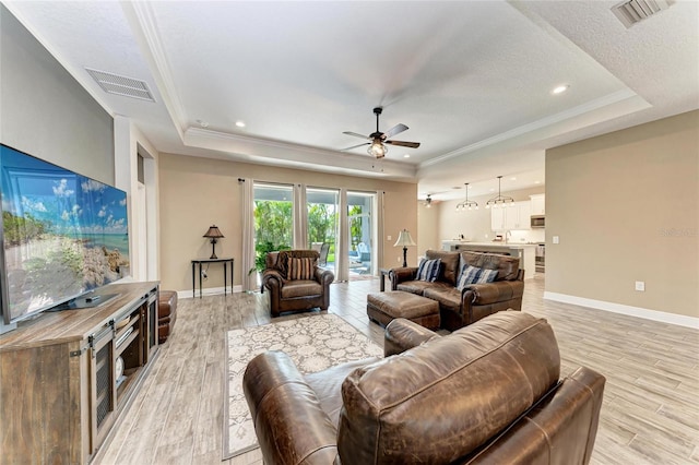 1219 Thornbury Dr, Parrish, FL 34219 - living room with a tray ceiling, a ceiling fan, light wood finished floors, ornamental molding, and a textured ceiling