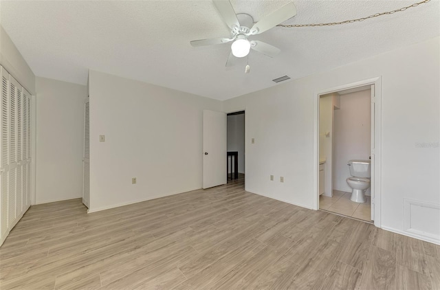 933 Sunridge Way Unit B5, Sarasota, FL 34234 - unfurnished bedroom with light wood-style floors, ensuite bathroom, a ceiling fan, and a textured ceiling