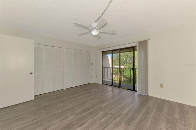 933 Sunridge Way Unit B5, Sarasota, FL 34234 - unfurnished bedroom featuring access to exterior, wood finished floors, two closets, and a textured ceiling