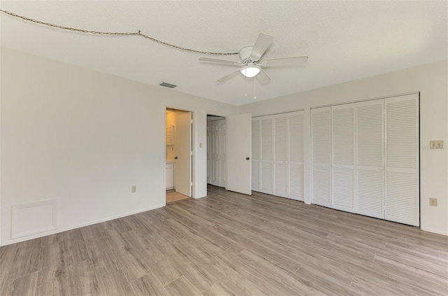 933 Sunridge Way Unit B5, Sarasota, FL 34234 - unfurnished bedroom with light wood-style floors, multiple closets, connected bathroom, and a ceiling fan