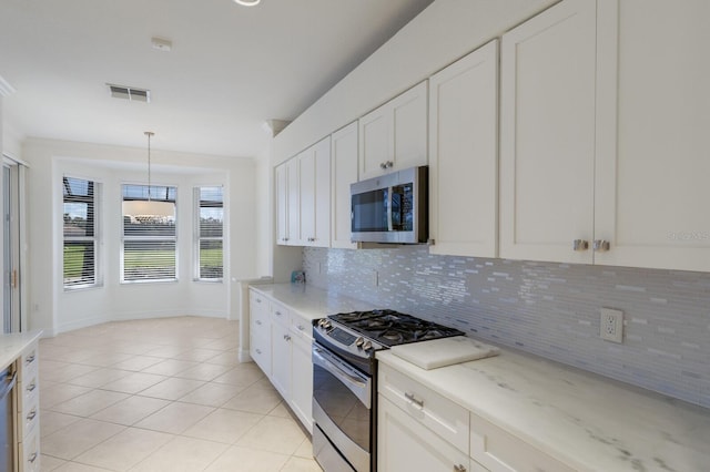 9719 Discovery Ter, Bradenton, FL 34212 - kitchen with stainless steel appliances, decorative backsplash, white cabinetry, and light tile patterned floors