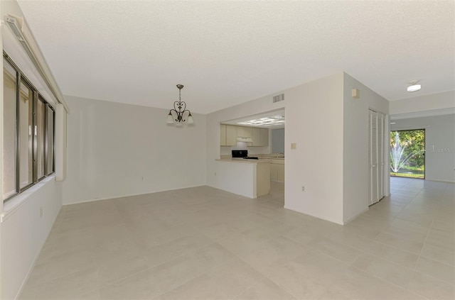 935 Sunridge Way Unit B4, Sarasota, FL 34234 - unfurnished living room featuring a chandelier, a textured ceiling, and light tile patterned floors