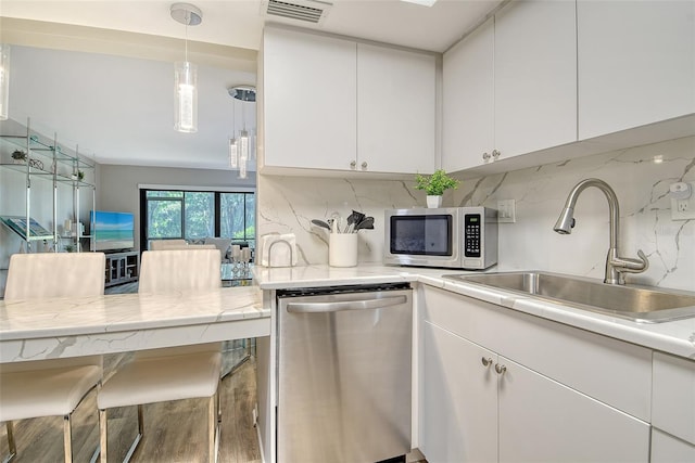 2055 Gulf Of Mexico Dr Unit G2-108, Longboat Key, FL 34228 - kitchen featuring stainless steel appliances, white cabinetry, decorative backsplash, wood finished floors, and decorative light fixtures