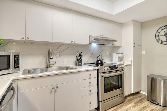2055 Gulf Of Mexico Dr Unit G2-108, Longboat Key, FL 34228 - kitchen featuring stainless steel appliances, under cabinet range hood, light wood-style floors, light countertops, and tasteful backsplash