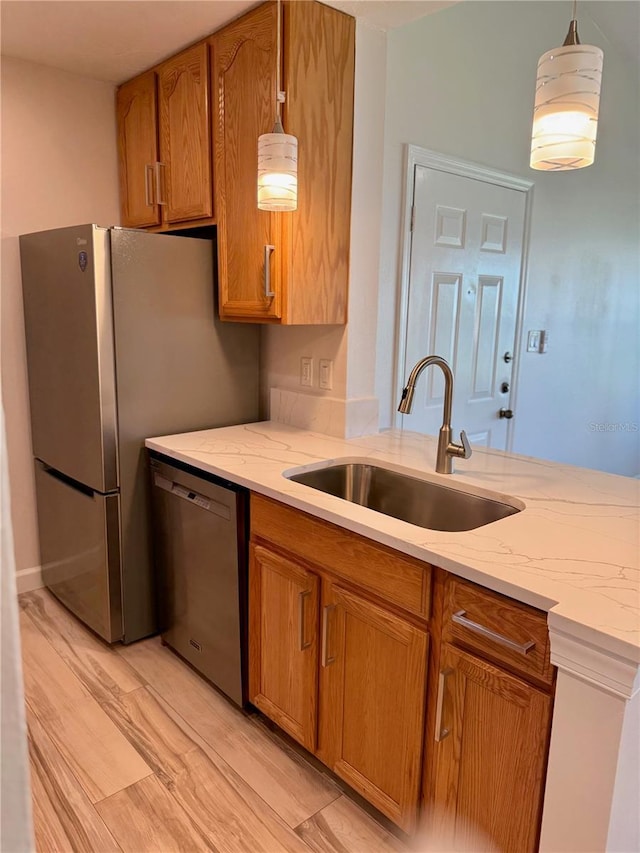 4037 Crockers Lake Blvd Unit 24, Sarasota, FL 34238 - kitchen with dishwasher, a sink, light stone counters, brown cabinetry, and hanging light fixtures