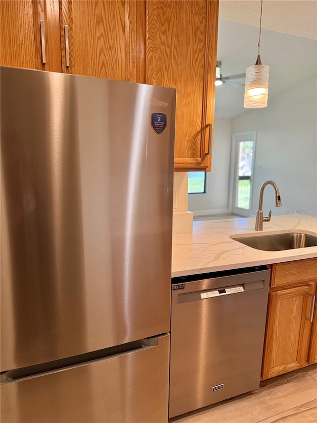 4037 Crockers Lake Blvd Unit 24, Sarasota, FL 34238 - kitchen with appliances with stainless steel finishes, a sink, light stone counters, and brown cabinets
