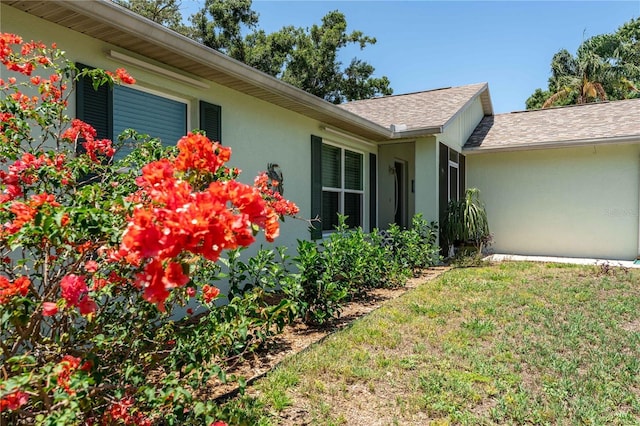 712 68th Ave W, Bradenton, FL 34207 - view of side of property with stucco siding, a lawn, and a shingled roof