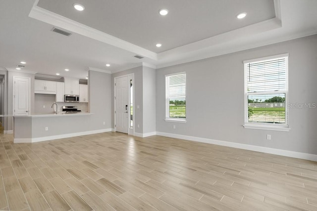 3204 Torta Ct, Bradenton, FL 34211 - unfurnished living room with a raised ceiling, crown molding, light wood-style flooring, and recessed lighting
