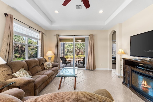 138 Tiziano Way N, Venice, FL 34275 - living area with ceiling fan, a tray ceiling, light tile patterned floors, a glass covered fireplace, and recessed lighting