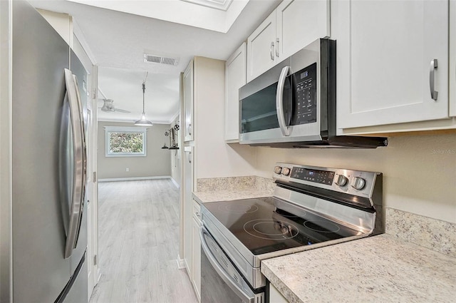 7211 Cloister Dr Unit 101, Sarasota, FL 34231 - kitchen with stainless steel appliances, light countertops, white cabinets, light wood-type flooring, and crown molding