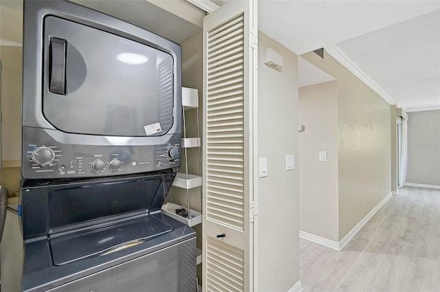 7211 Cloister Dr Unit 101, Sarasota, FL 34231 - laundry area featuring stacked washing machine and dryer, wood finished floors, baseboards, and crown molding