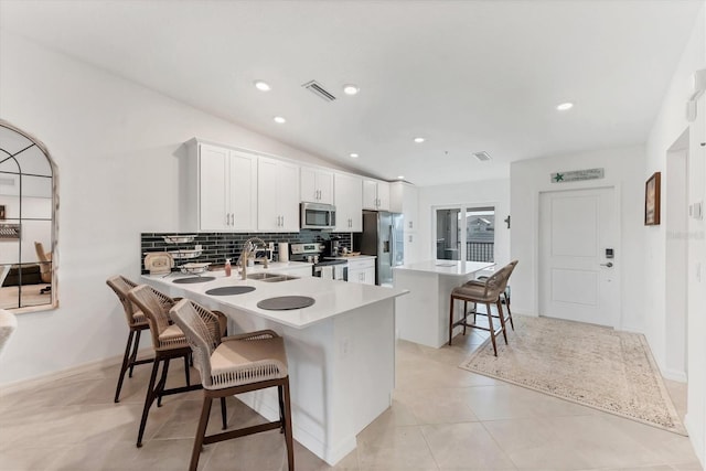 14257 Heritage Landing Blvd Unit 1122, Punta Gorda, FL 33955 - kitchen with stainless steel appliances, a sink, a kitchen breakfast bar, backsplash, and white cabinets