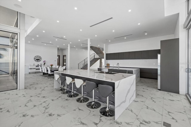 4035 Bay Shore Rd, Sarasota, FL 34234 - kitchen featuring modern cabinets, a large island, black electric cooktop, dark cabinetry, and light marble finish flooring