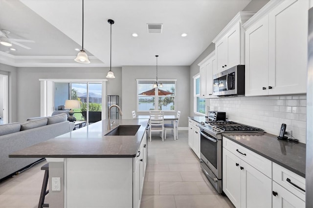 13549 Old Creek Ct, Parrish, FL 34219 - kitchen featuring appliances with stainless steel finishes, a sink, dark countertops, tasteful backsplash, and a kitchen island with sink