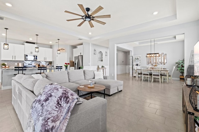 17547 Cantarina Cv, Bradenton, FL 34211 - living area with a tray ceiling, recessed lighting, ceiling fan, a chandelier, and light tile patterned floors