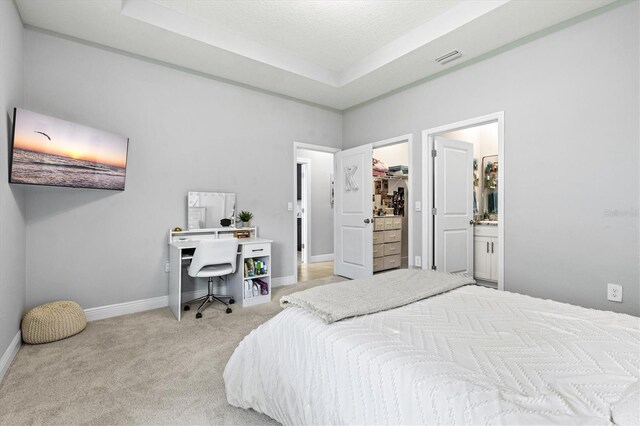 17547 Cantarina Cv, Bradenton, FL 34211 - bedroom with carpet flooring, a desk, a tray ceiling, a spacious closet, and ensuite bath