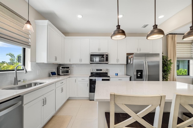 6239 Baywood Ct, Bradenton, FL 34211 - kitchen with appliances with stainless steel finishes, backsplash, light tile patterned flooring, a breakfast bar, and white cabinets