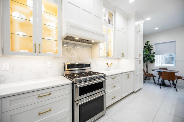 5074 Flagstone Dr, Sarasota, FL 34238 - kitchen with range with two ovens, tasteful backsplash, light tile patterned floors, white cabinets, and light stone counters