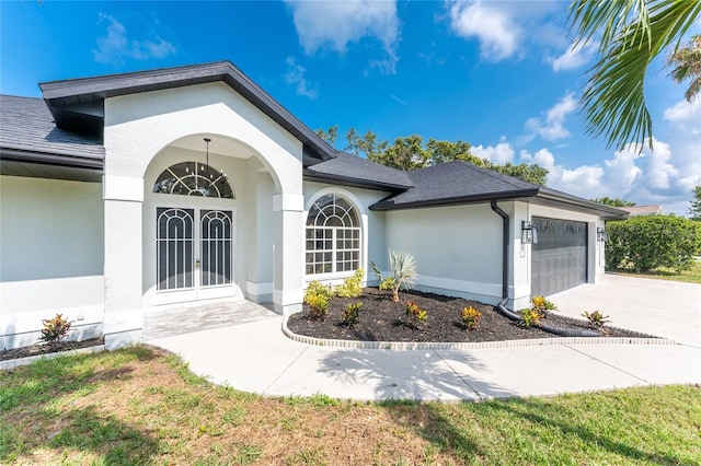 10055 Franklin Dr, Englewood, FL 34224 - view of front of home featuring french doors, a garage, driveway, and stucco siding