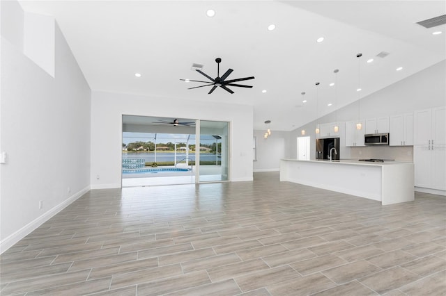 10055 Franklin Dr, Englewood, FL 34224 - unfurnished living room with ceiling fan, baseboards, recessed lighting, high vaulted ceiling, and a sink