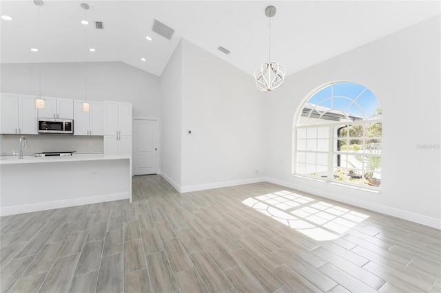 10055 Franklin Dr, Englewood, FL 34224 - unfurnished living room featuring high vaulted ceiling, light wood finished floors, a chandelier, baseboards, and recessed lighting