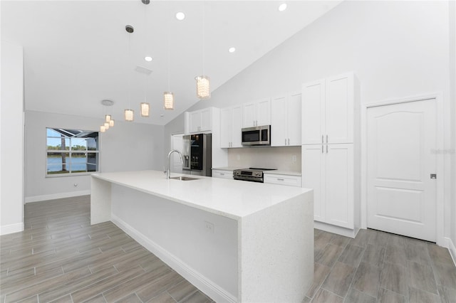 10055 Franklin Dr, Englewood, FL 34224 - kitchen featuring appliances with stainless steel finishes, a sink, white cabinetry, a spacious island, and light wood finished floors