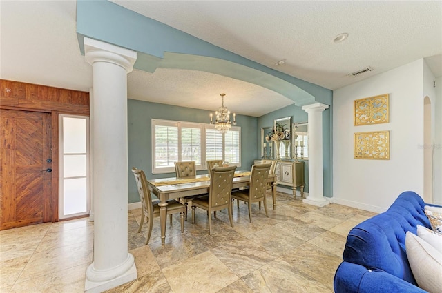 2726 Desoto Rd, Sarasota, FL 34234 - dining area with decorative columns, a textured ceiling, arched walkways, baseboards, and a chandelier